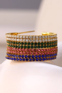 Macro detail of gold C-shape earrings with multi-row colorful cubic zirconia pavé setting