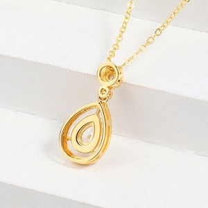 Elegante collana con ciondolo a goccia dorata e cristallo lucido su sfondo di pietra