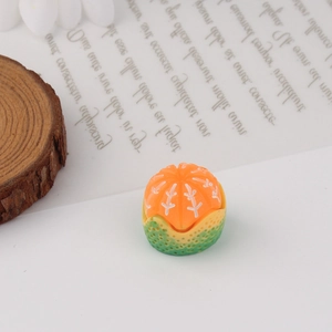 Close-up of miniature orange resin cactus ornament with green textured base on white stones