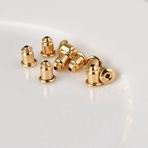 Macro-opname van acht gouden kogelvormige metalen oorbelstoppers op een witte schaal