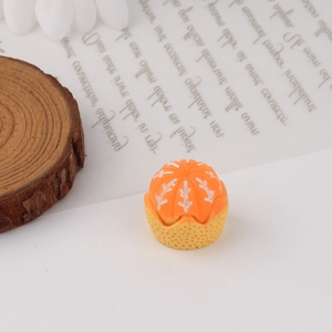Detailed view of orange succulent resin miniature on a wood slice with white pebbles