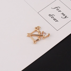 Detailed close-up of a gold-plated bow and arrow pendant with a clear zircon stone