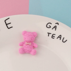 Makroaufnahme eines rosa Bären-Accessoires aus Harz mit Smile-Schriftzug für DIY-Dekor