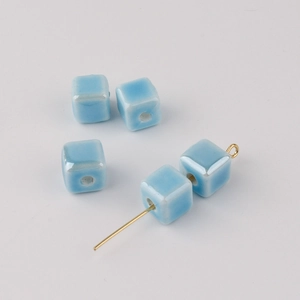Macro view of blue cube ceramic beads with gold metal pins for DIY jewelry making