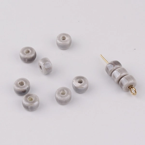 Macro shot of creamy ceramic abacus beads on a golden pin for jewelry making