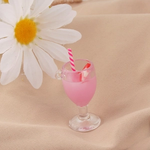 Macro di un ciondolo a calice di succo rosa in miniatura in resina con cannuccia e frutta