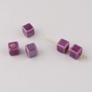 Macro detail of five purple square ceramic beads with central holes for DIY jewelry