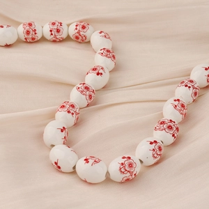 Detalle macro de cuentas de cerámica blanca con flores de ciruelo sobre tela seda