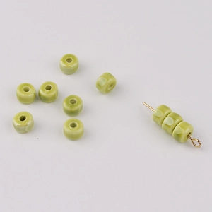 Close-up of grass green glazed ceramic spacer beads for DIY jewelry making and crafts