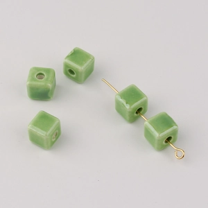 Macro detail of light green cube ceramic beads on a gold pin for DIY jewelry making