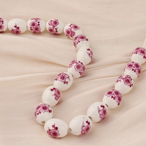 Detalle macro de cuentas de cerámica blanca con motivos florales morados para joyas