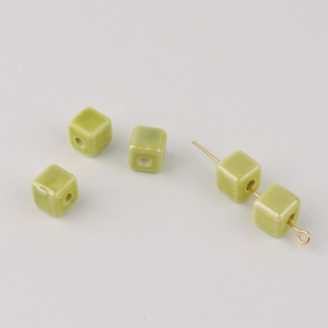 Detail of green square ceramic beads with center hole on gold pins for DIY jewelry