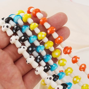 Hand holding colorful mushroom glass beads with polka dots for DIY jewelry making