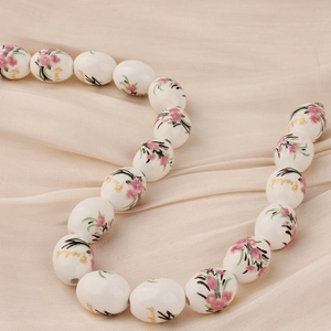 Detalle de cuentas de cerámica con motivos florales rosas y texto Orchid sobre seda