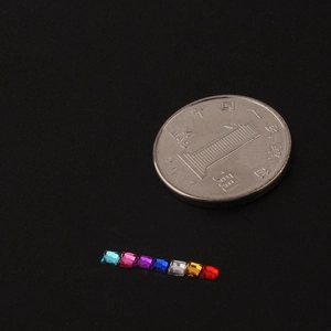 Mini 2mm square acrylic rhinestones for nail art displayed next to a coin for scale