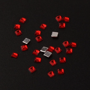 Macro shot of 2mm red square acrylic rhinestones with faceted surface and flat back