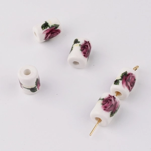 Detail showing cylindrical ceramic beads with purple rose prints on a white glazed surface