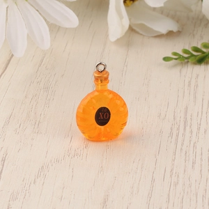 Nahaufnahme eines Miniatur-Likörflaschen-Anhängers aus orangefarbenem Harz mit XO-Logo