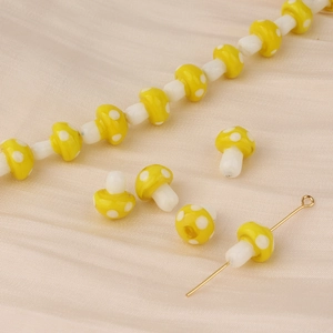 Macro detail of yellow polka dot mushroom glass beads with gold metal T-pins on velvet