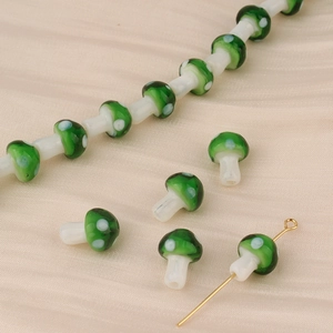 Macro detail of green mushroom glass beads on silk for DIY jewelry making and crafting