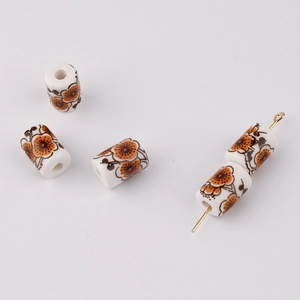 Close-up of cylindrical ceramic beads with orange floral prints for DIY jewelry making