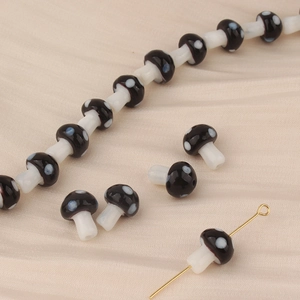 Detail of small mushroom glass beads for DIY jewelry with black polka dot design