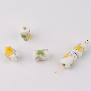 Detailed macro view of white cylindrical ceramic beads with delicate yellow floral patterns