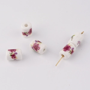 Macro detail of cylindrical ceramic beads with purple floral patterns and threading hole