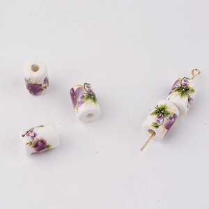 Detailed close-up of cylindrical ceramic beads with purple floral patterns for DIY jewelry