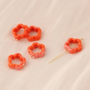 Detailansicht orangefarbener Keramik-Blumenperlen mit seitlichen Löchern für DIY-Schmuck
