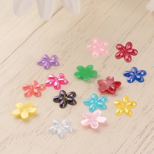 Macro shot of colorful resin flower charms for DIY crafts on a light wood background