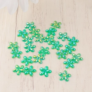 Flat lay of AB iridescent green resin flower charms for nail art and DIY crafts