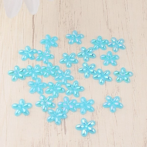 Macro detail of AB coated light blue resin flower charms on light wood background
