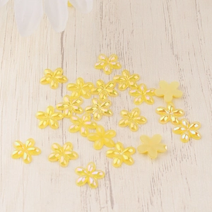 Macro detail of yellow resin 5-petal flowers with iridescent pearl finish for DIY nail art