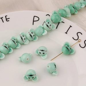 Dettaglio di perline in ceramica a forma di topo verde menta con fori per gioielli fai-da-te
