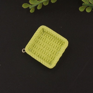 Macro detail of a light green square resin pendant with woven texture and metal ring