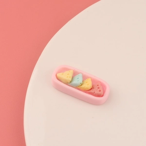 Macro shot of colorful resin cheese charms on a pink tray for DIY crafts decoration