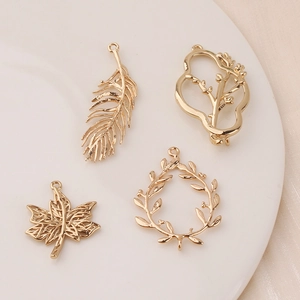 Golden leaf and feather metal charms on a white plate for DIY jewelry making accessories
