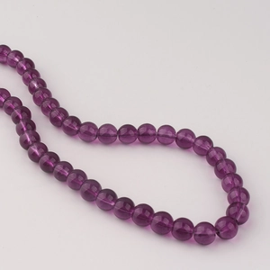 Gros plan de perles en verre violet translucide de 8 mm pour la création de bijoux DIY