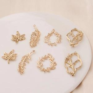 Golden leaf and feather charms set on white plate for DIY jewelry making accessories