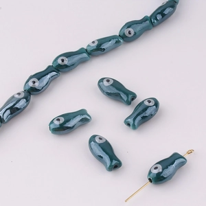 Detail of dark cyan glazed fish beads with shiny finish for DIY jewelry making and crafts