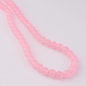 Gros plan de perles en verre rose translucide sur un fil pour la création de bijoux