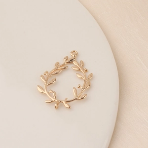 Macro shot of a golden olive leaf wreath pendant for DIY jewelry making on white stone