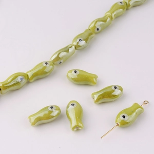 Macro shot of green fish ceramic beads showing the straight hole structure for DIY jewelry