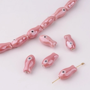 Close-up of pink ceramic fish beads with glazed finish for handmade DIY jewelry crafting