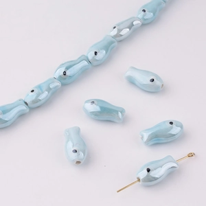 Detailed macro view of light blue fish ceramic beads with lustrous pearl glaze for DIY jewelry