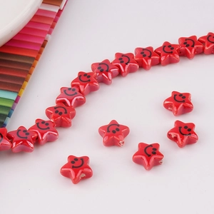 Close-up of red star-shaped ceramic beads with smiley face for DIY jewelry making