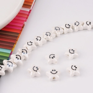 Close-up of white star-shaped ceramic smile face beads for DIY jewelry making and crafts