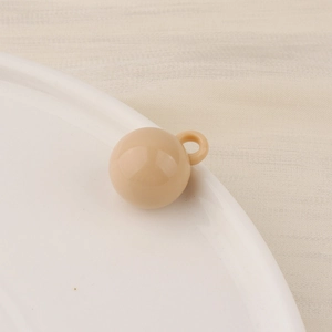 Detailed macro view of a nude candy-colored resin bead with a small loop for DIY jewelry