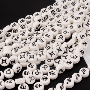 Macro shot of white circular ceramic beads with black printed zodiac sign symbols